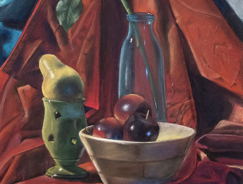 "Blue Glass," a drawing by MSU sophomore art/graphic design major Emily R. Harms of Madison, is a colorful still life - shows wooden bowl with 3 red apples in front, green glass cup behind on left with a pear resting on top, blue see-through milk-type glass container at center back with a single stem with leaves coming out of it; burgundy drapery is the backdrop; touch of blue seen at top left corner