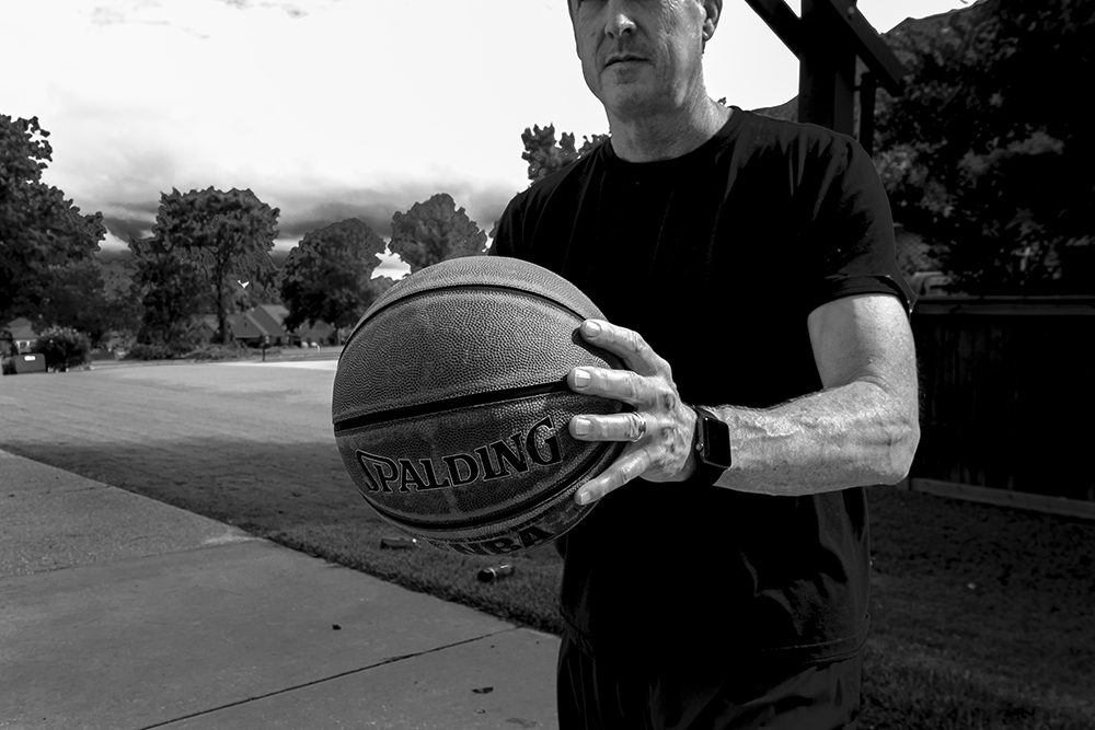 A black and white photographed image of a man holding a basketball.