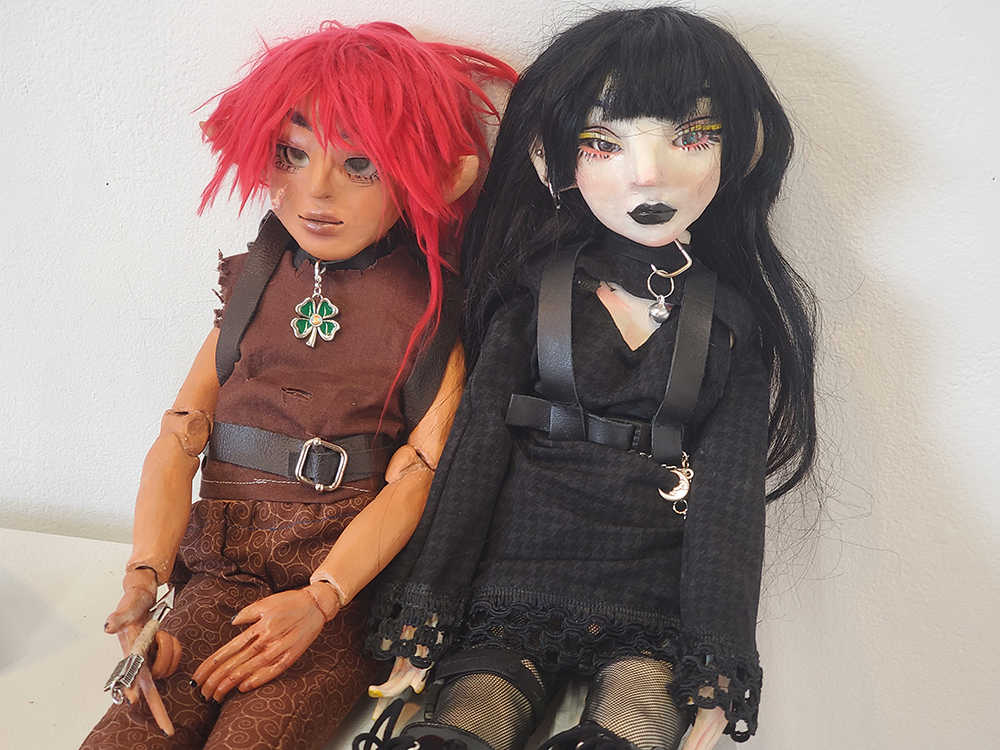 Two ceramic dolls decorated with different styles. One is an elf and the other wears punk attire. 