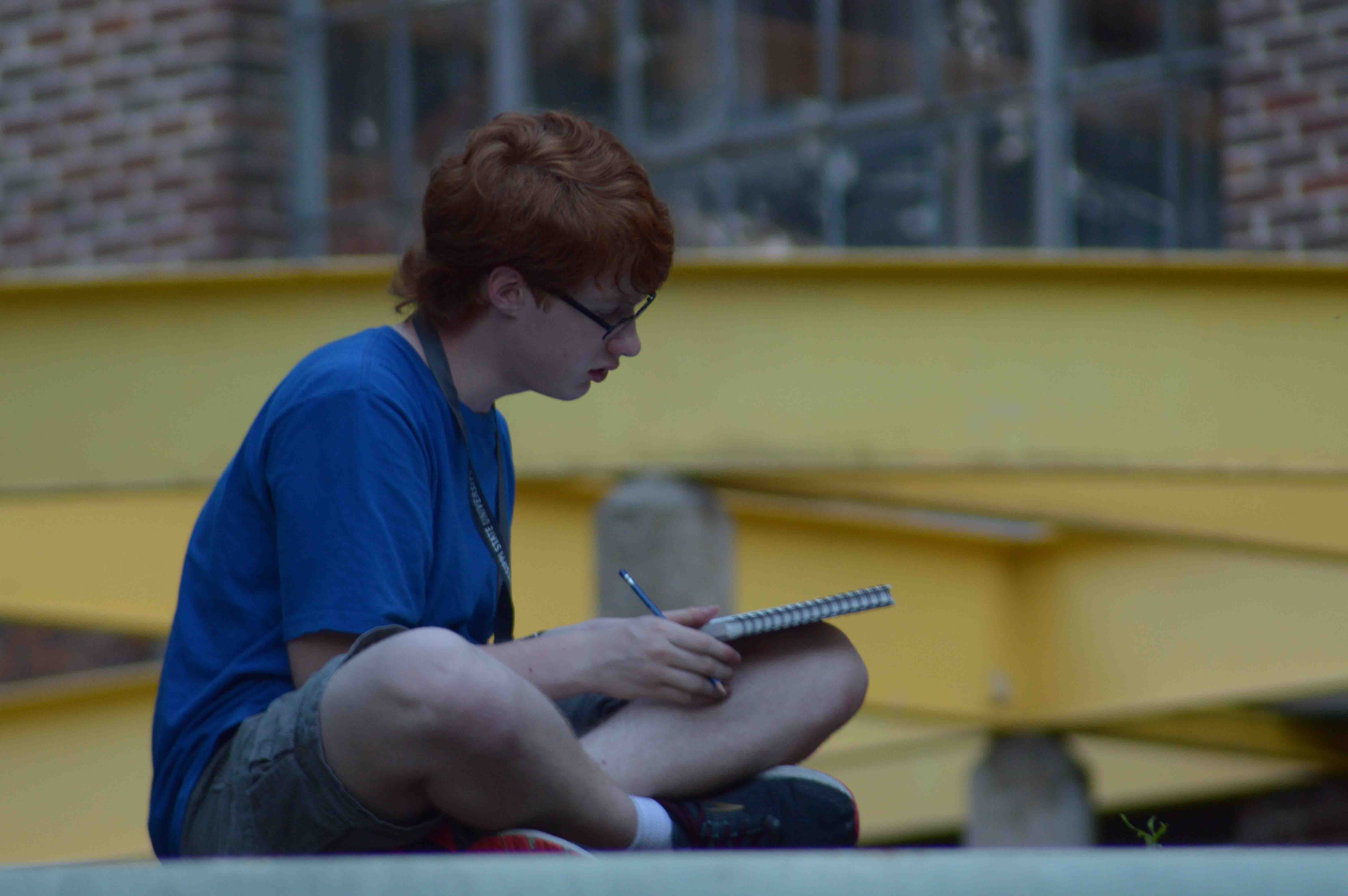 Student sitting and sketching in blue shirt
