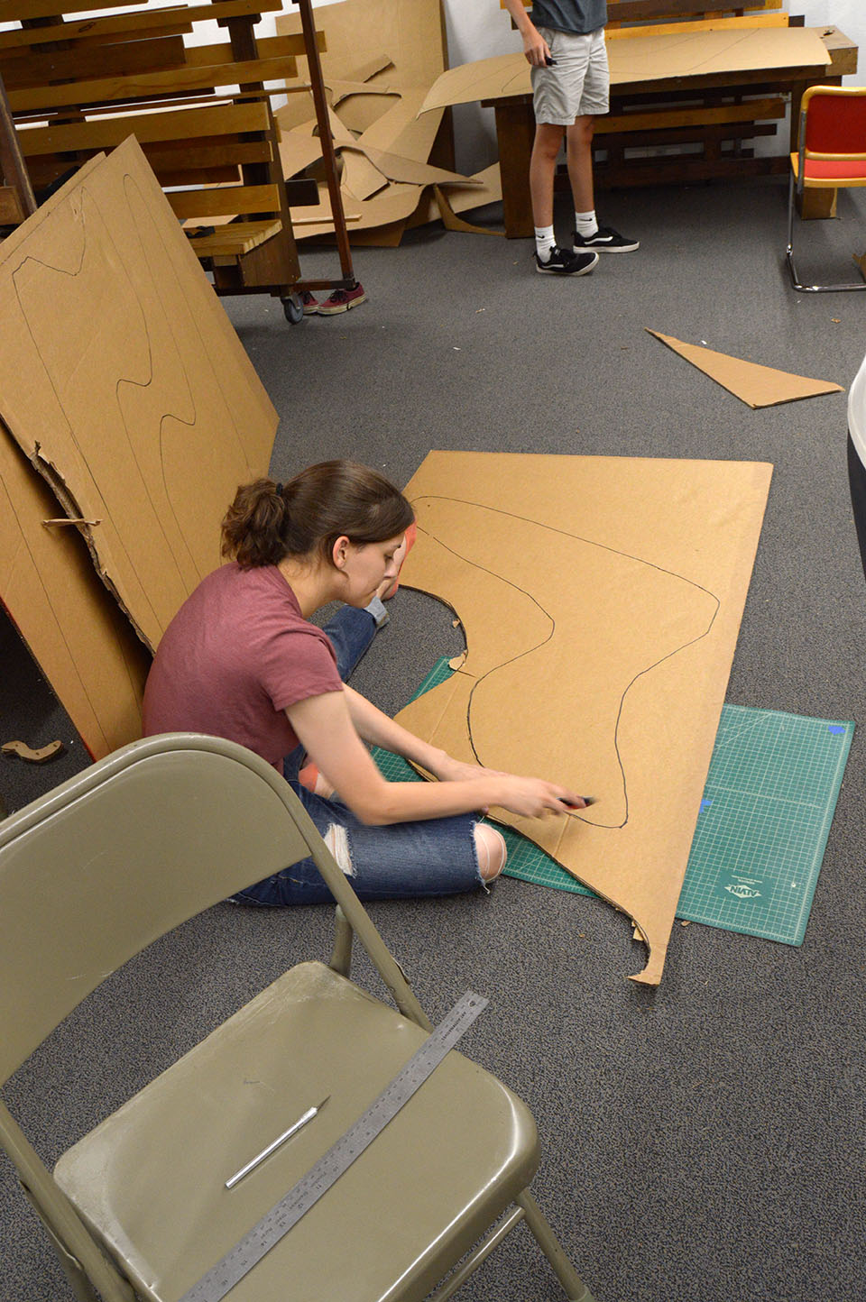 student sitting on floor cutting out chair pattern