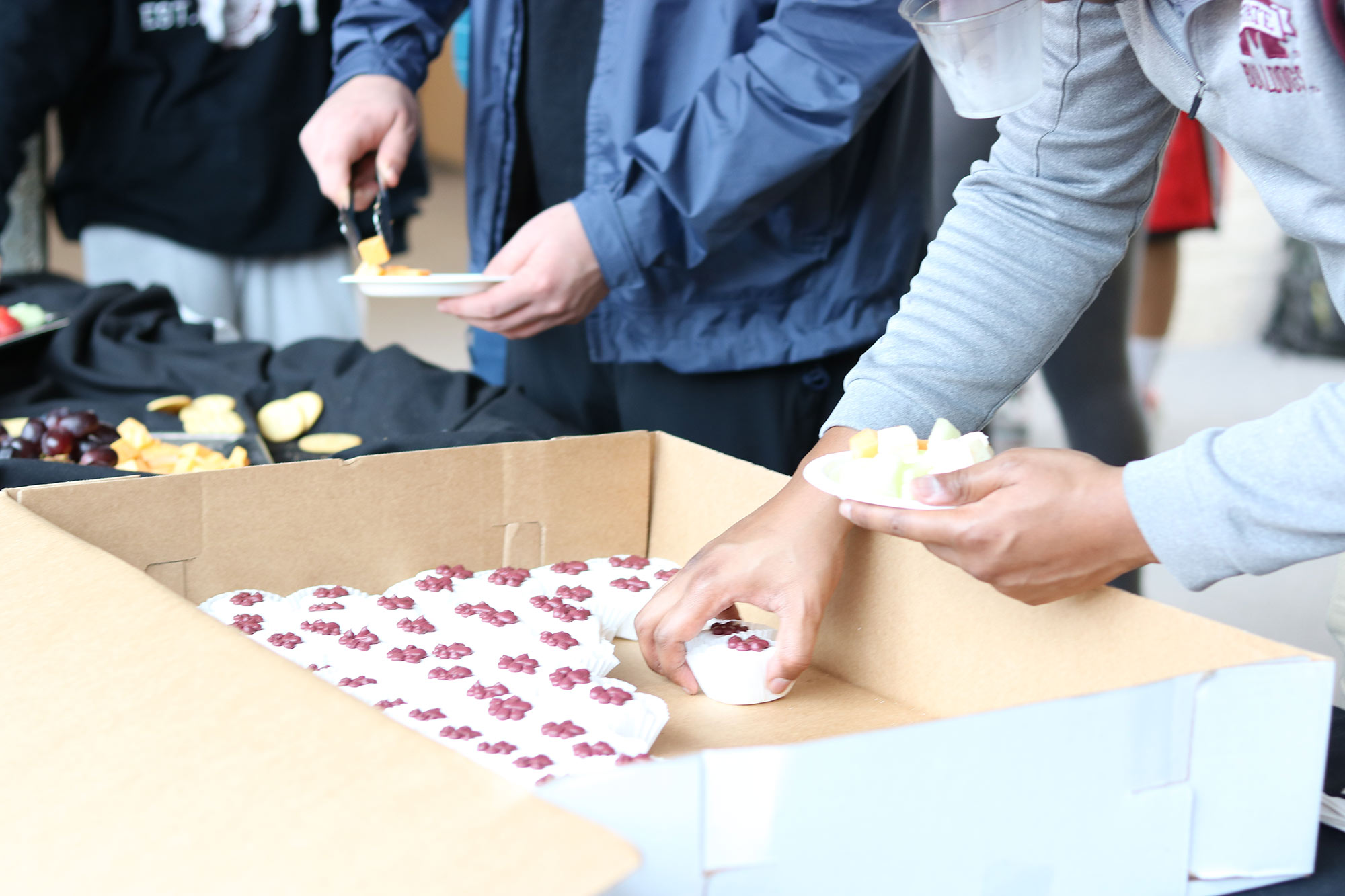 guests take cupcakes/food from a table outside of &quot;The Work of Philip Freelon&quot; exhibit during a reception in he Charlotte and Richard McNeel Gallery on the second floor of Giles Hall.