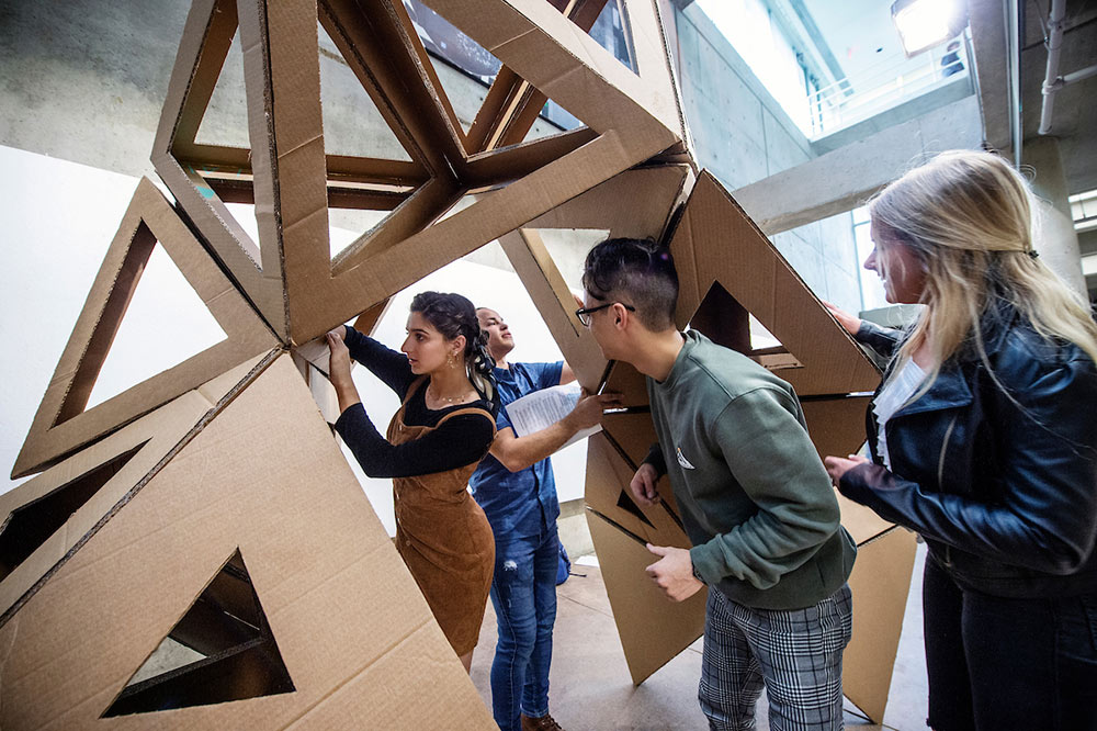 students working on cardboard structure in arch shape