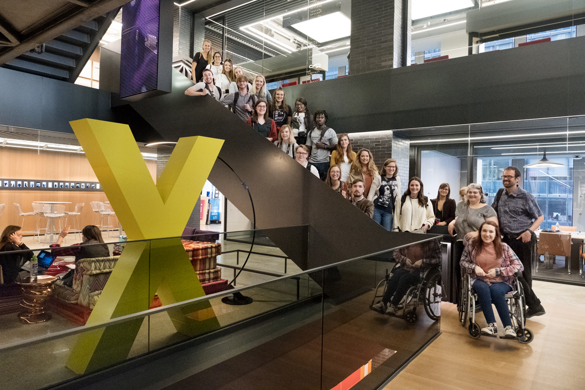 20 art students line up the stairs for a group portrait in the central atrium of the dramatic and modern Gensler design firm.