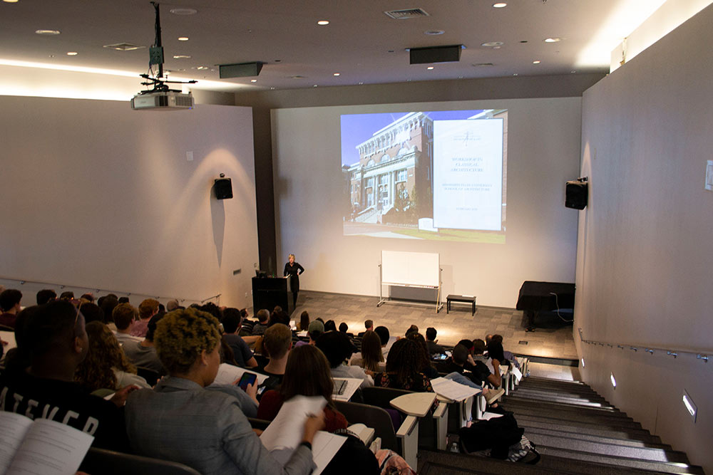 a view from the back of the Robert and Freda Harrison Auditorium in Giles Hall with a presenter at the lectern