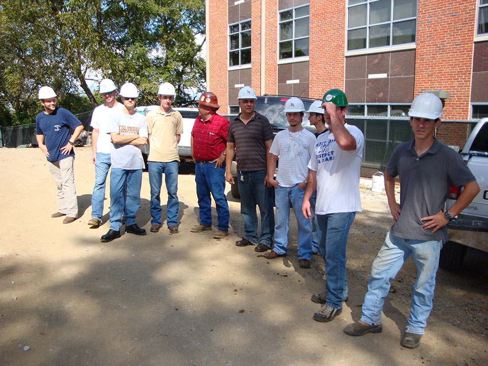 students wearing hard hats tour outside facility