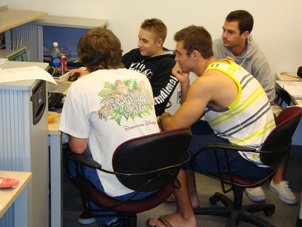 students gather around laptop