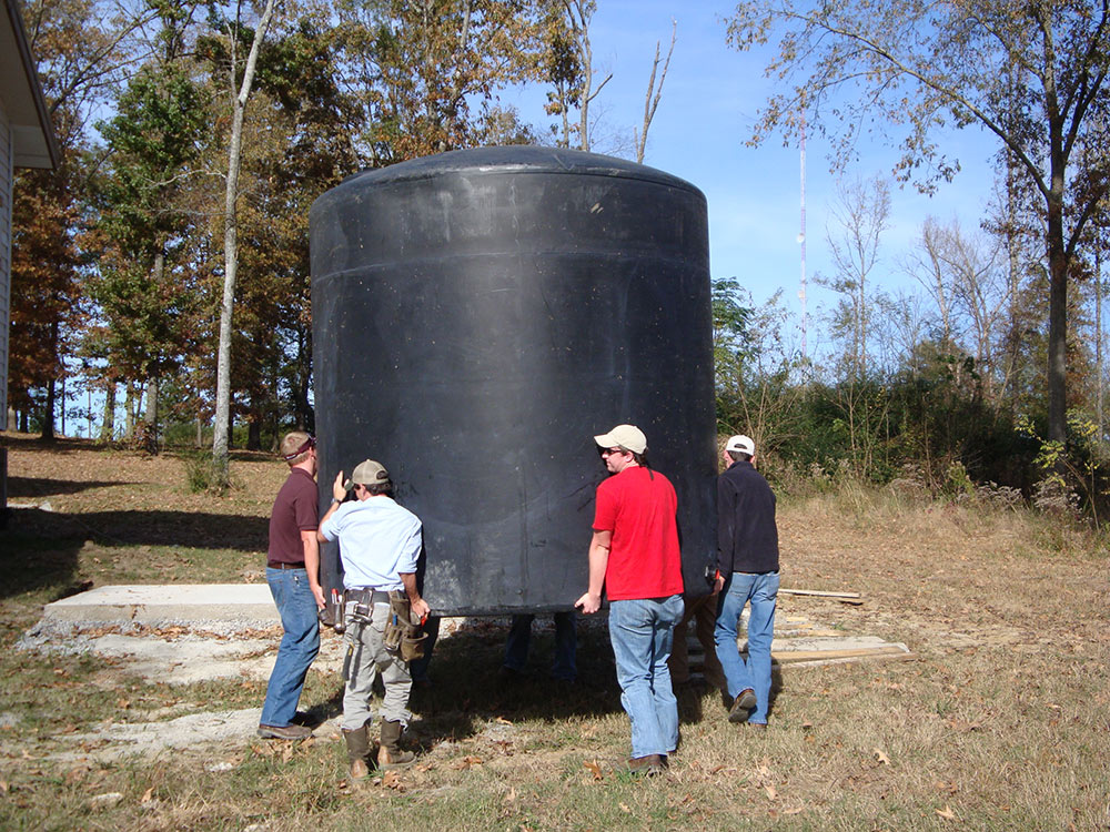 people lift large black cylinder