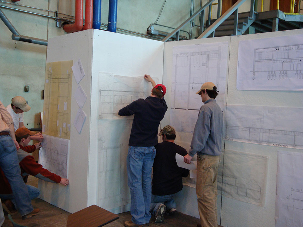 students gathered around project on wall