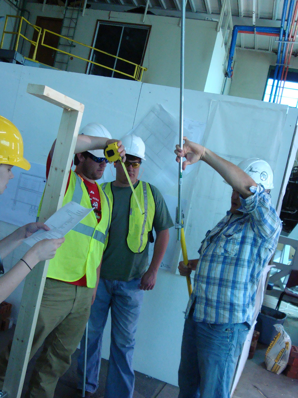 group in hart hats works on construction project - measuring