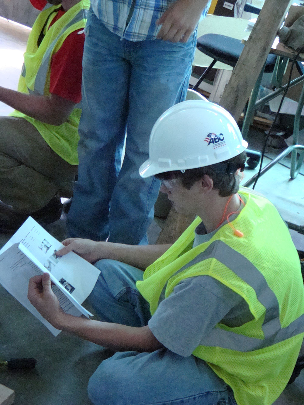 student in construction hat reads manual
