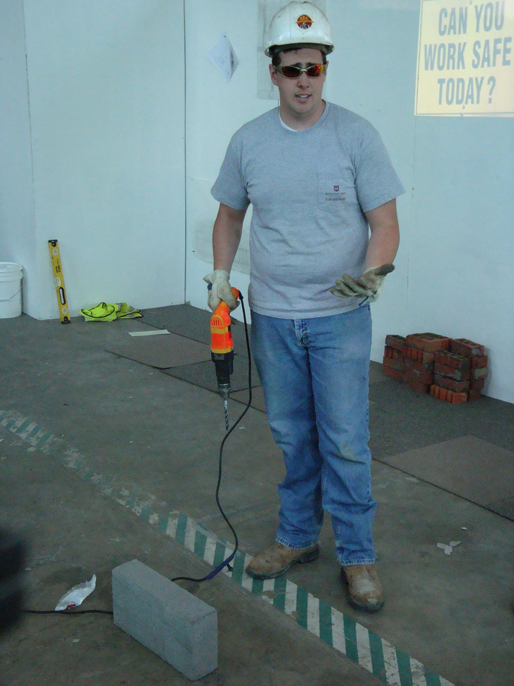 person wearing construction hat, holding tool
