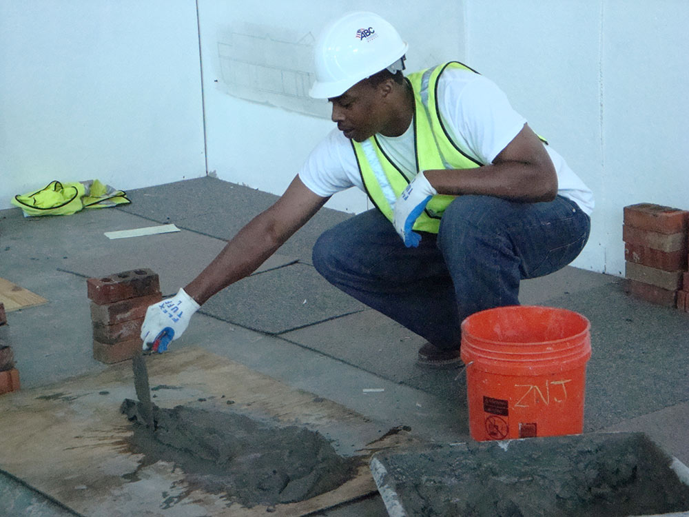 person spreading concrete with shovel