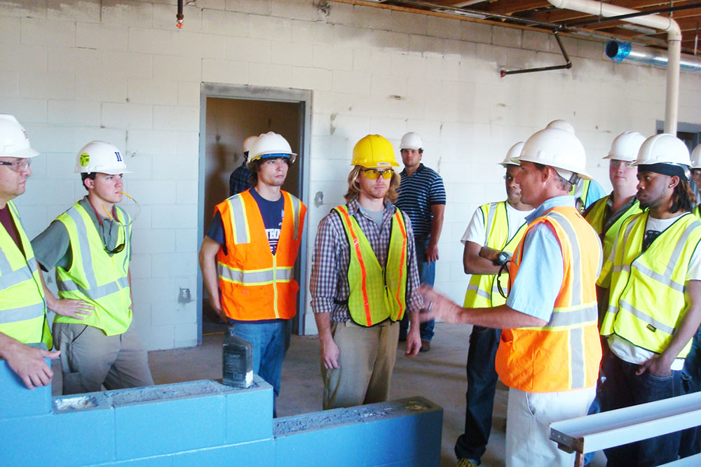group listens to construction professional on field trip