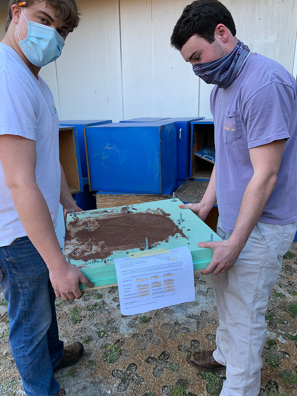 two students move their concrete disk form filled with concrete