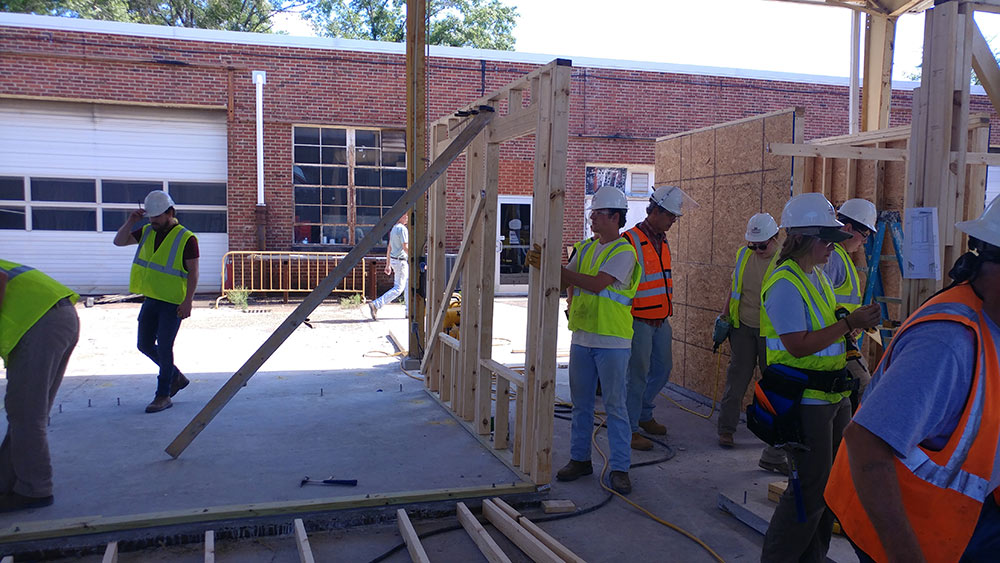 students in construction PPE work outside of Howell Building on wood frame