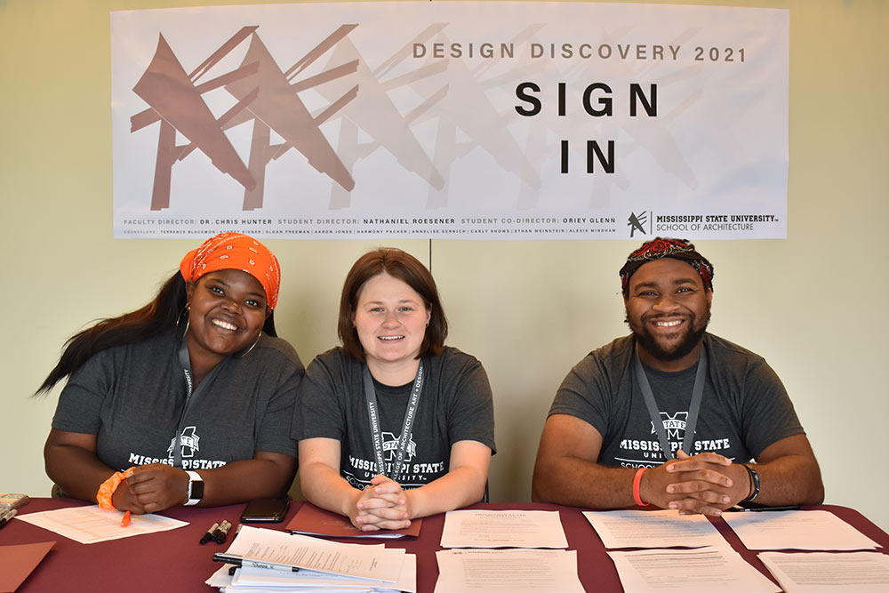 three counselors for Design Discovery sit at the &quot;sign-in&quot; table