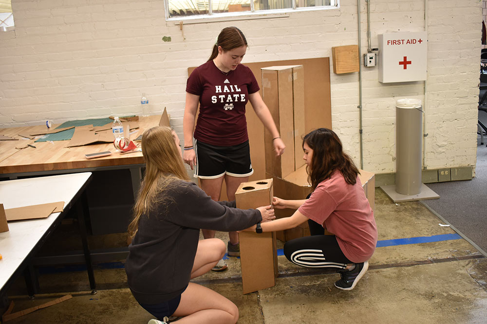 team of 3 campers works to complete their cardboard lounge device