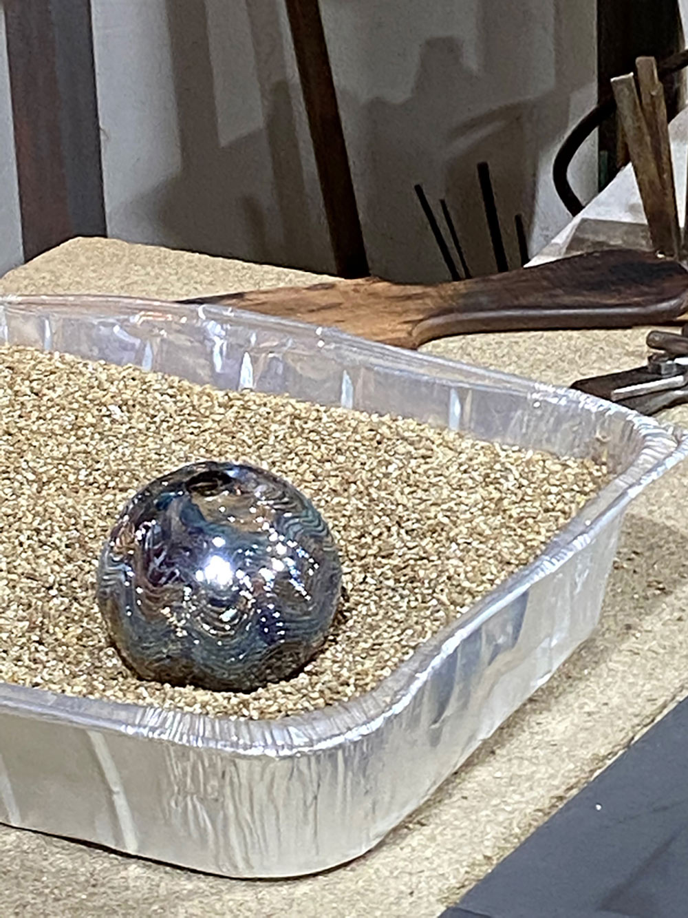 glass ornament sits in container of what looks like kitty litter