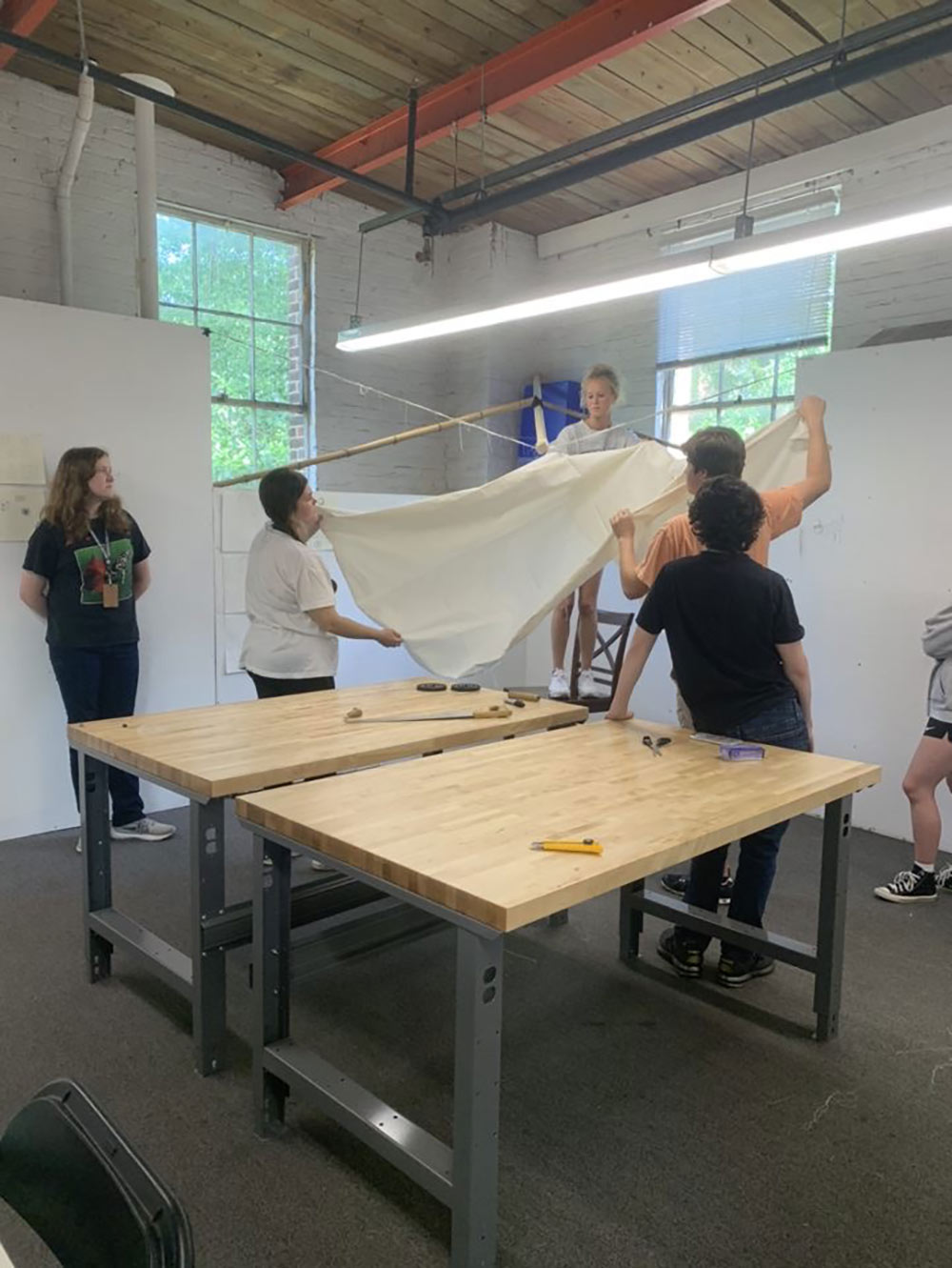 group holds a pice of white fabric, working on instant environment