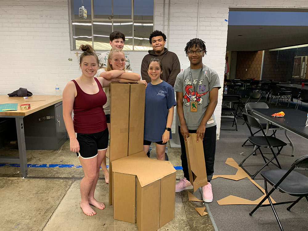 campers pose with their lounge device made out of cardboard
