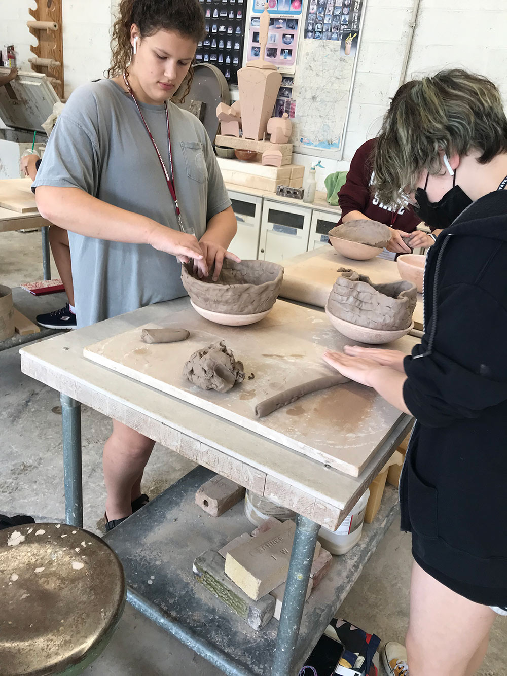 students work to mold ceramic bowls with hands