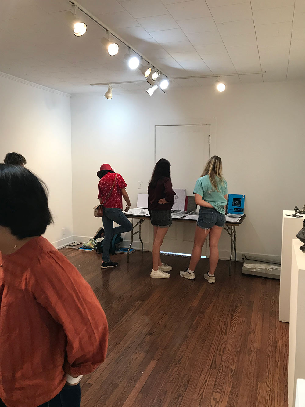 people view work on table Visual Arts Center Gallery as campers look on