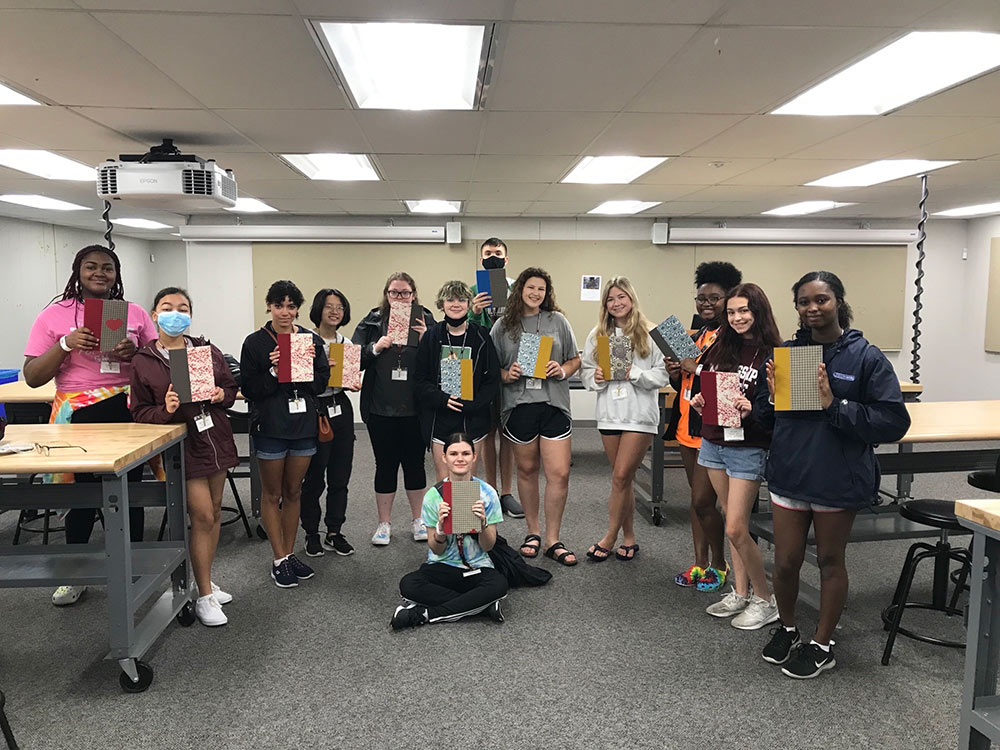 13 campers pose with their finished books in the classroom