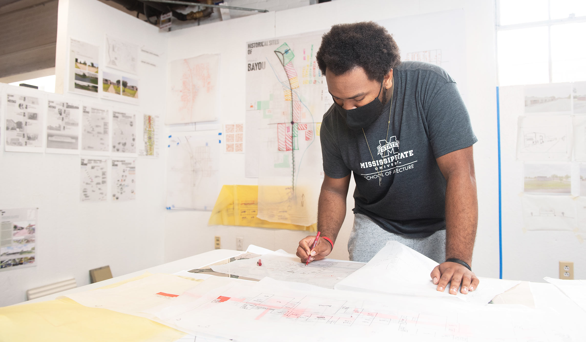 Terrance Blackmon leans over drafting table writing with pen