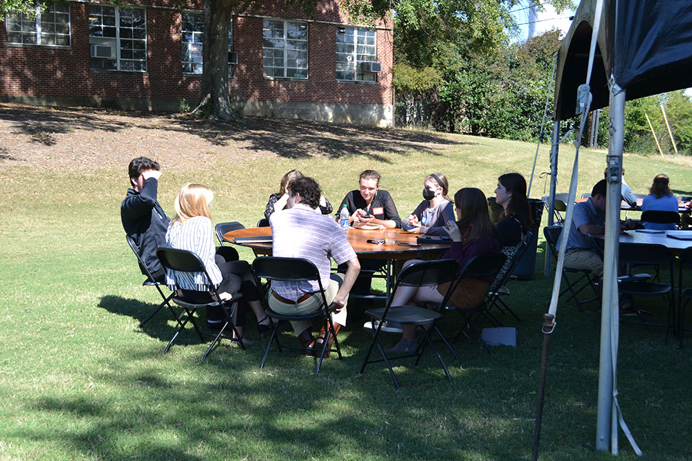 Participants of the Design Leadership Foundation’s Professional Horizons Workshop sit at a table outside of Giles under the tent.