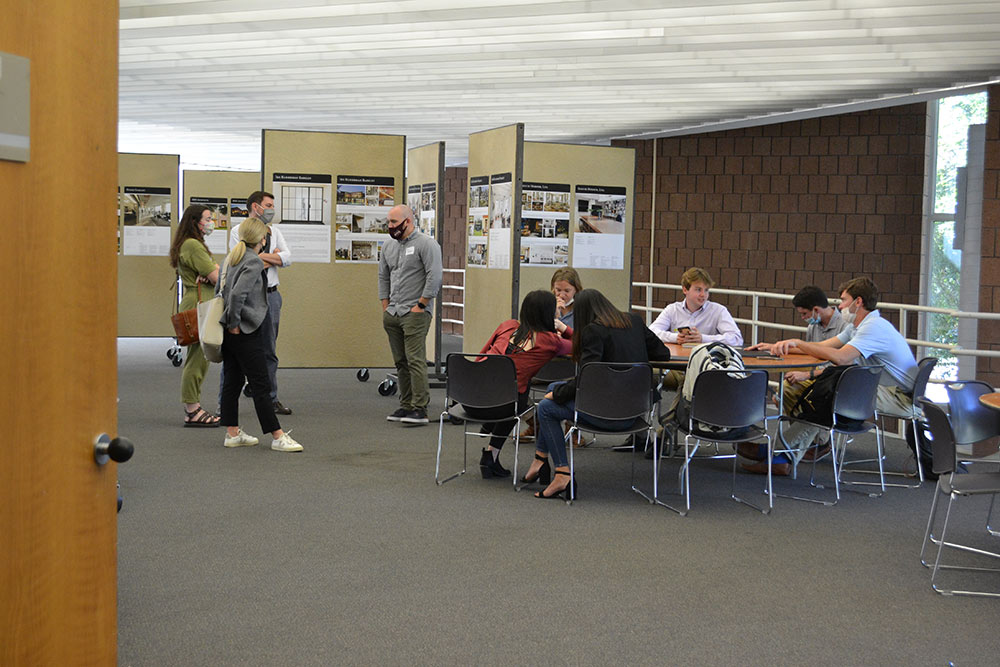 A group of participants sit around a table in Giles while discussing with a design professional.