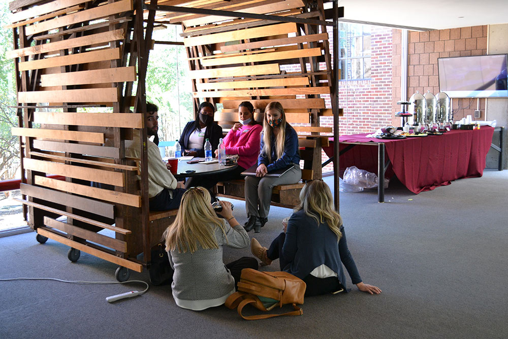 A group of participants sit in a covered booth made of wood in Giles.