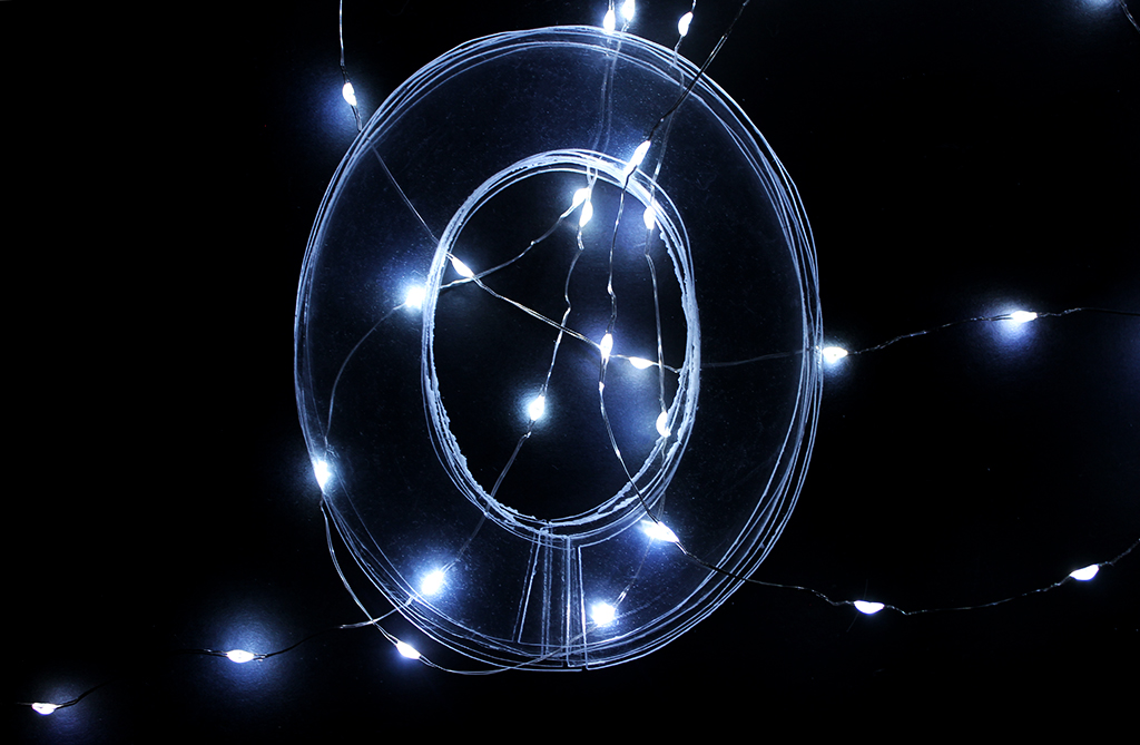 Black and white digital image of the letter &quot;O&quot; surrounded by small lights.