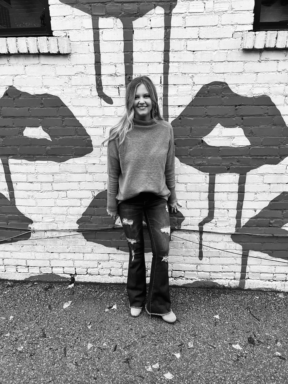 Skylynn Russell stands for photo in front of bricks painted with lips