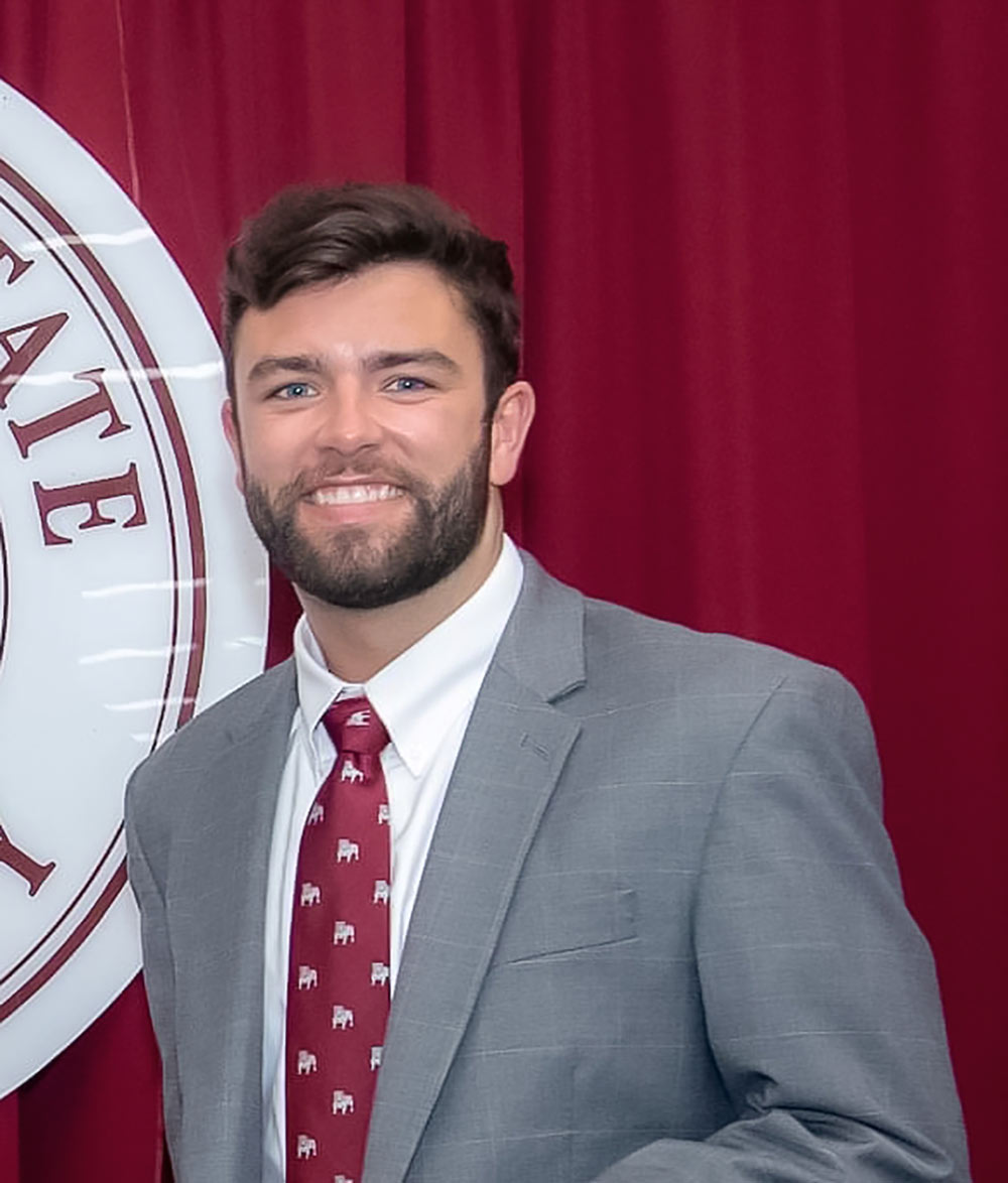 headshot of Ryan Smith with part of MSU seal to left