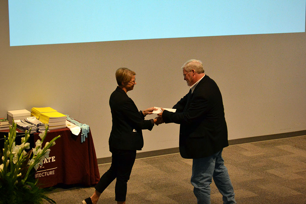 Dr. Angi Elsea Bourgeois shakes hands with Mark Vaughan