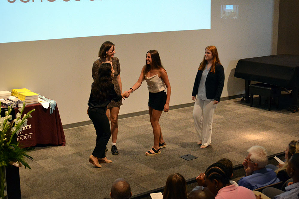 Professor Silvina Lopez Barrera presents the First-Year Faculty Book Award to Tess Bruno, Heather Papizan, and Abby Williams