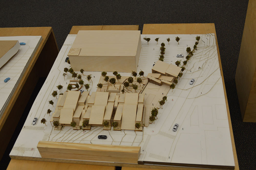 A wooden model that depicts a building with surrounding shrubbery.