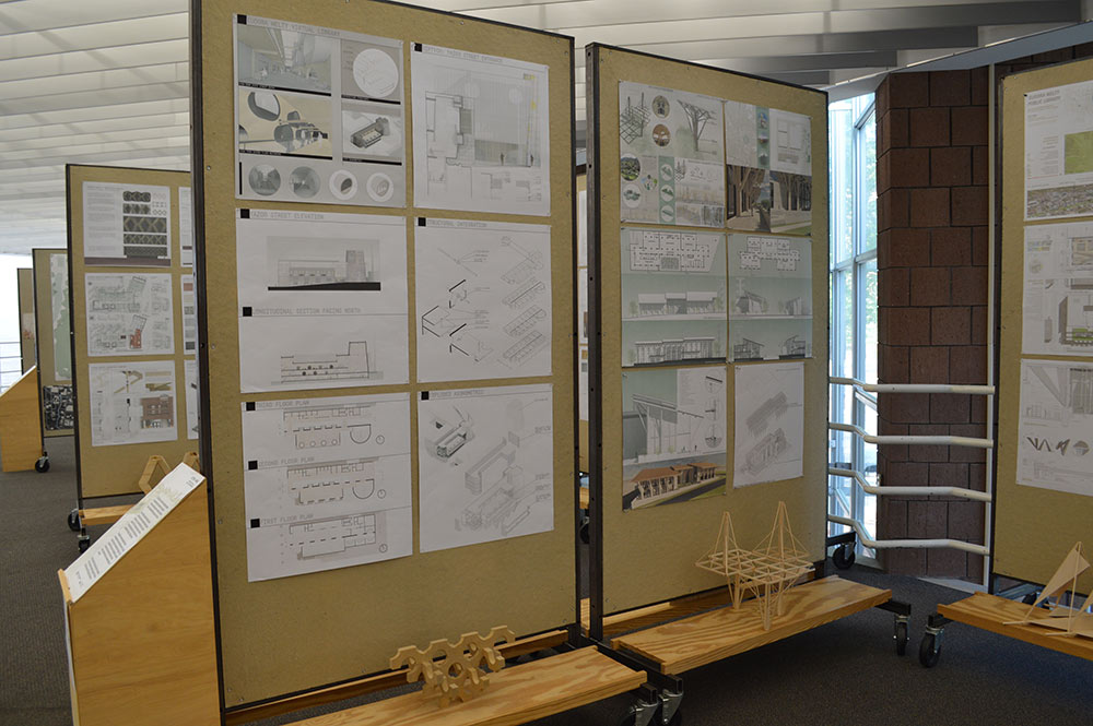 Two pin up boards in the gallery that feature information about the projects displayed in front of them.