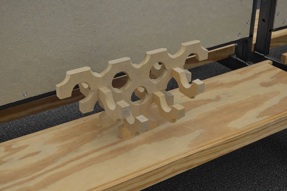 A wooden model on display that has holes carved out of it and fits into another piece like a puzzle.