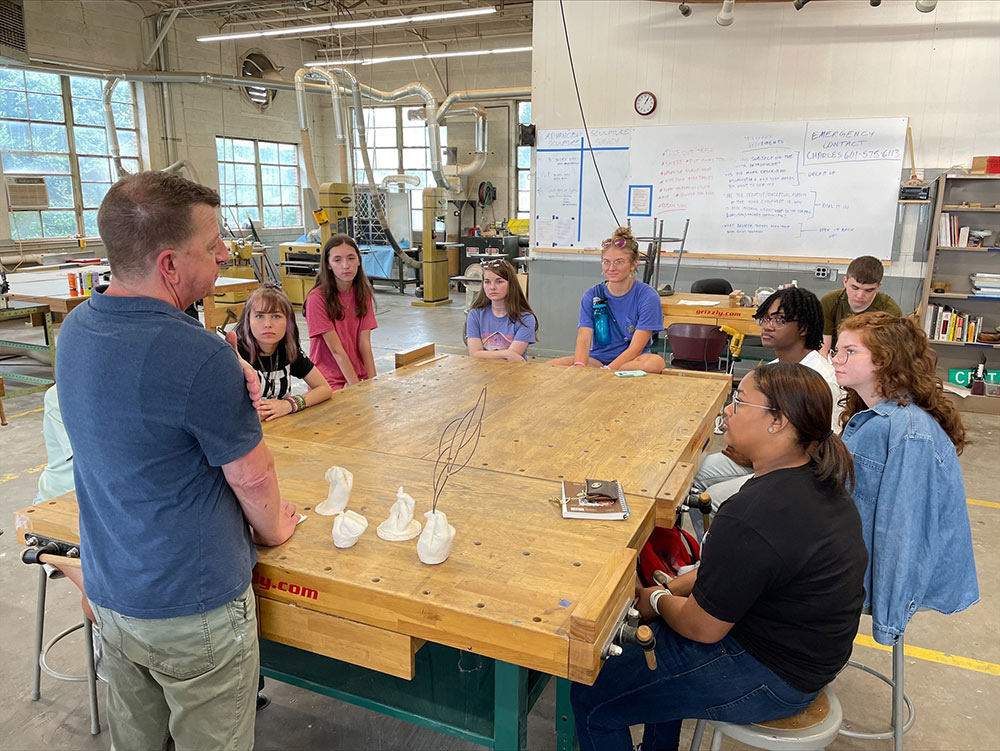 Critz Campbell, front left, teaches students sitting around a table at InVision art summer camp 2022