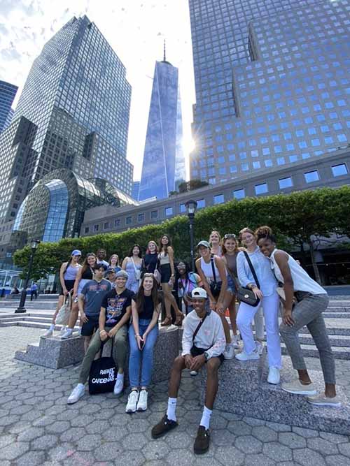 The group of students stand for a group picture with the One World Trade Center building in the background.
