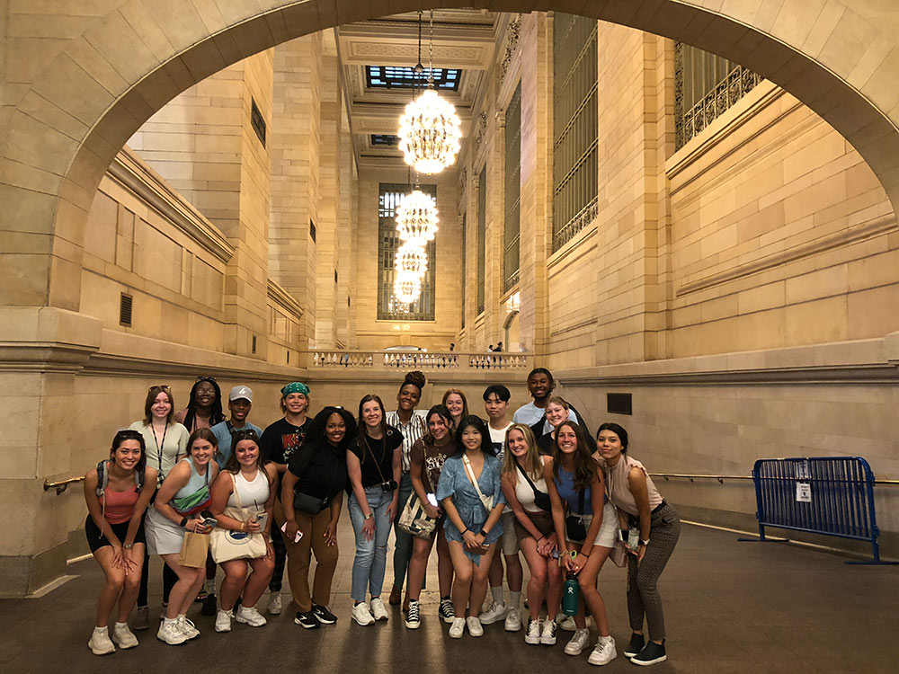 students pose in building in NYC under arch