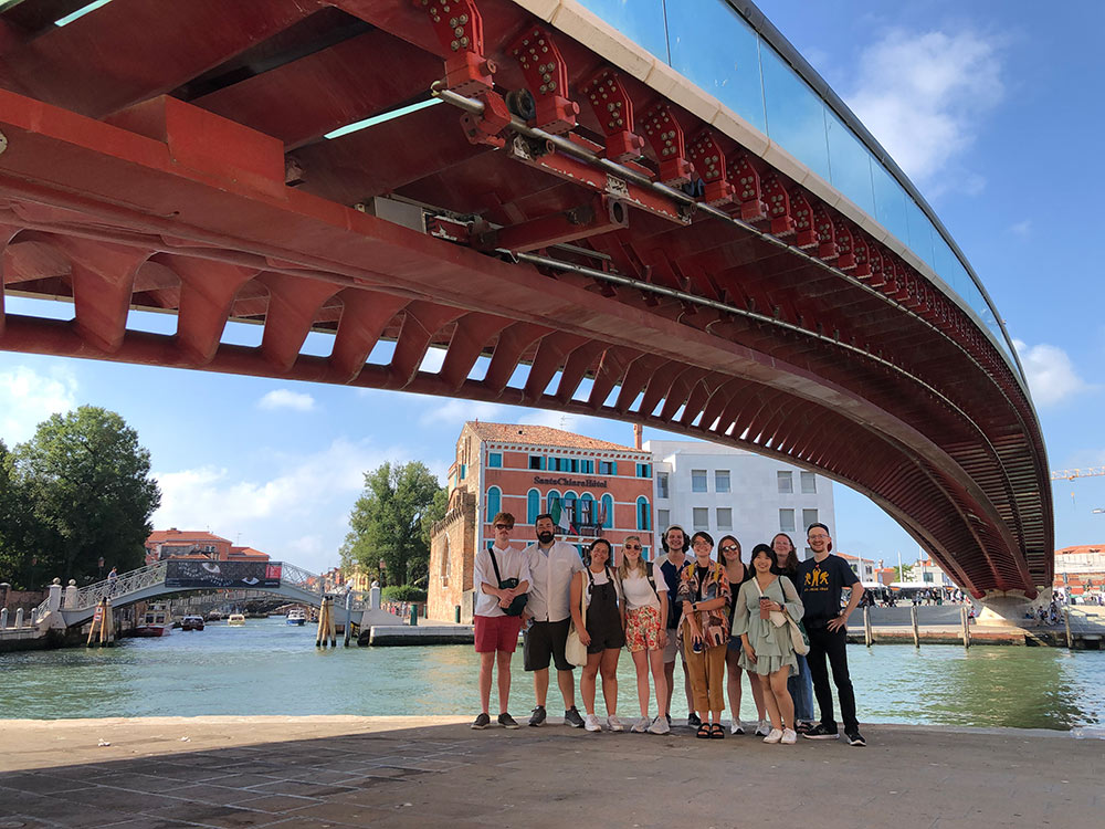 Group poses by canal under bridge