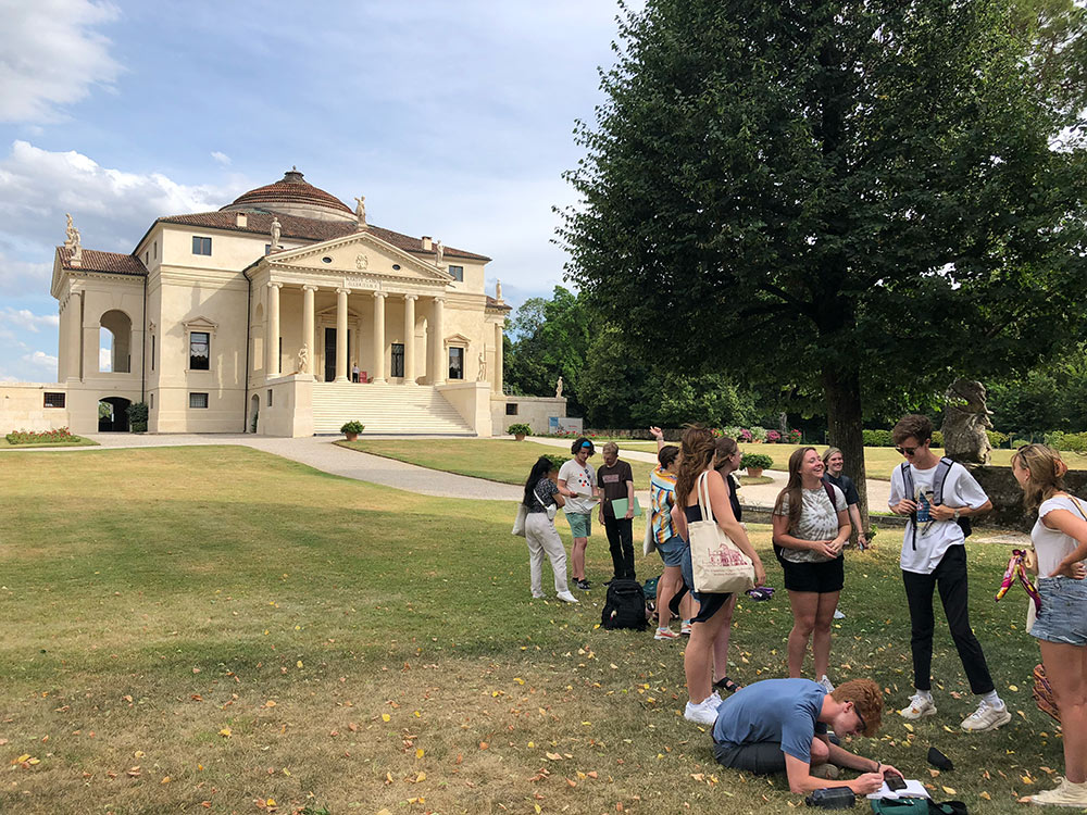 Students rest and sketch on lawn
