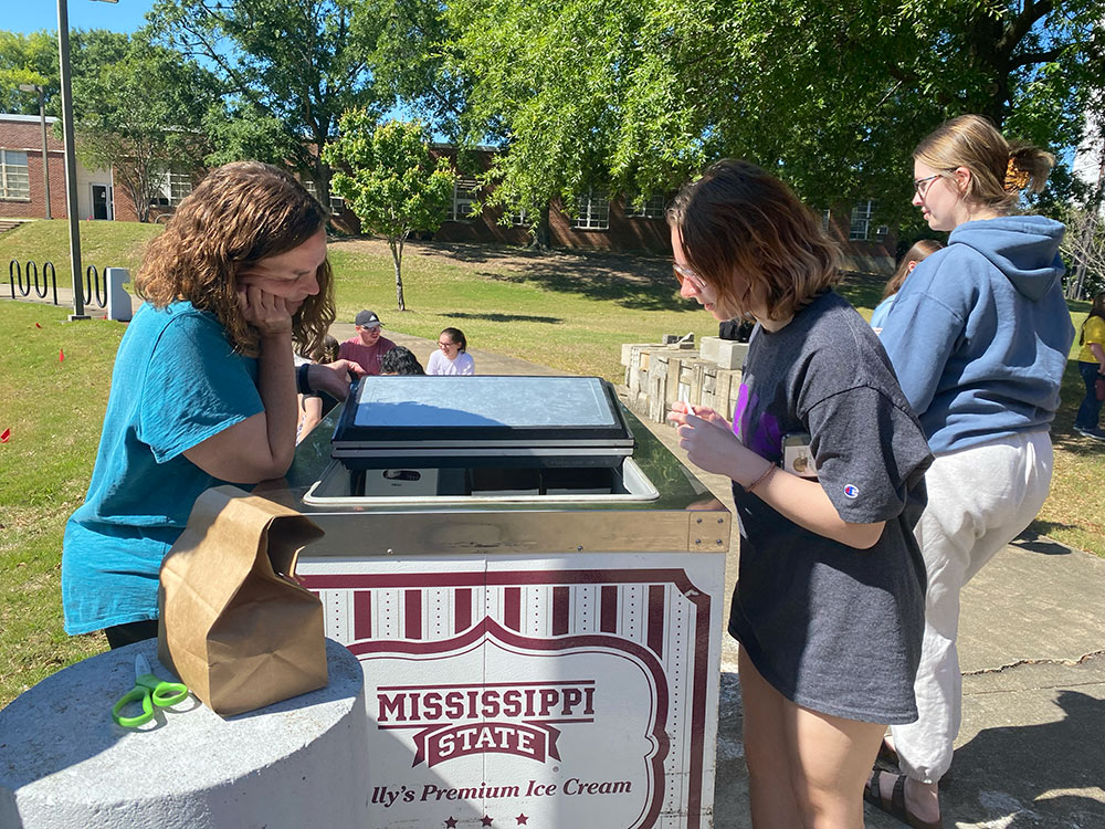 Jessica Rahim, left, helps students choose MSU ice cream flavor