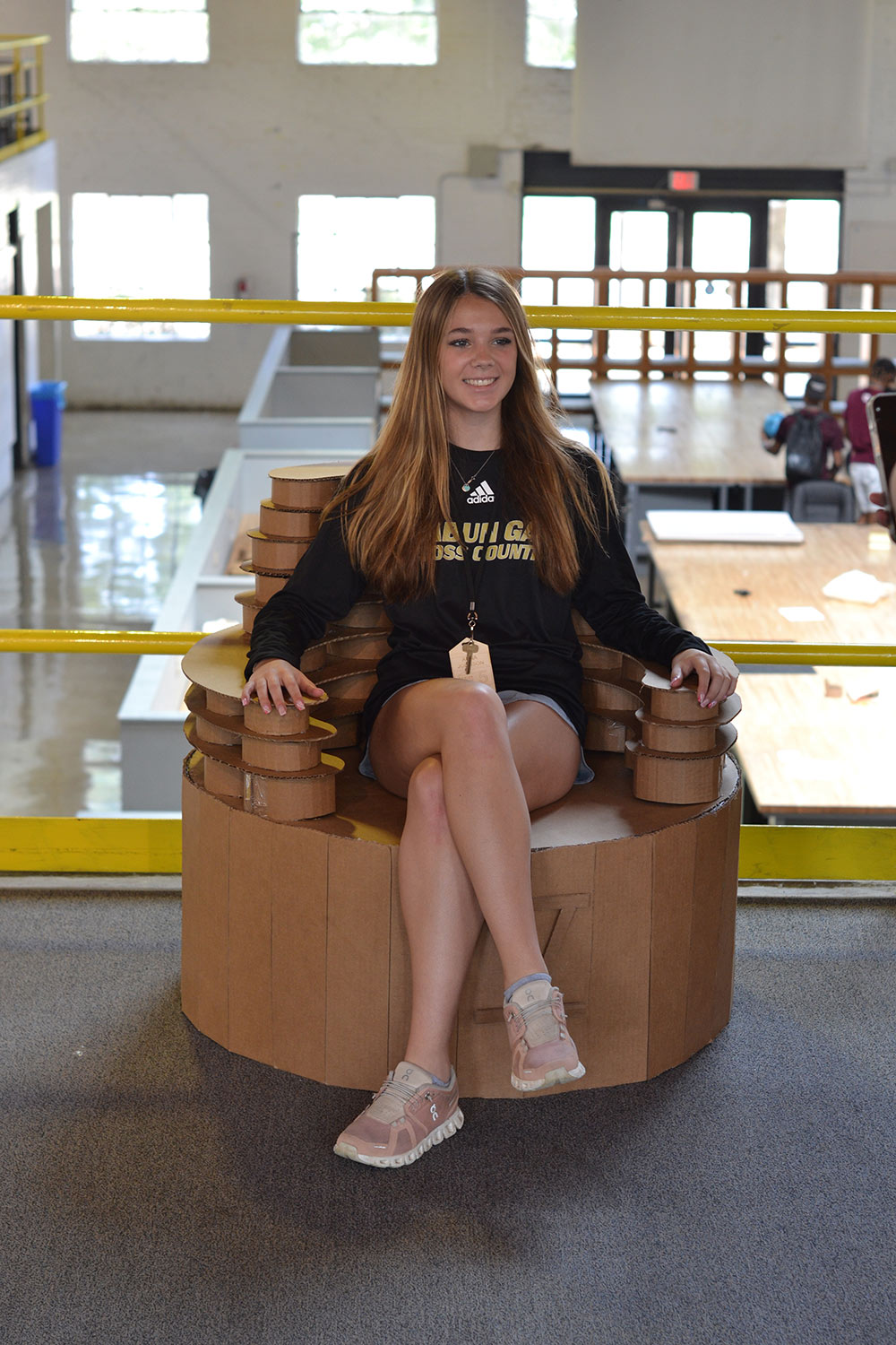 Design Discovery camper sits on her cardboard chair project.