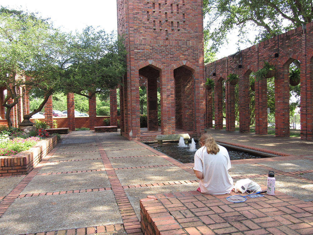 Design Discovery camper sitting in the Chapel of memories courtyards, sketching in her notebook.