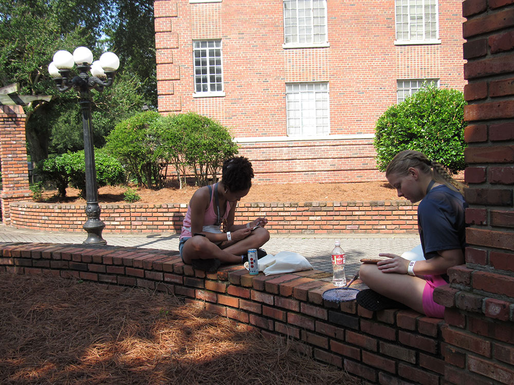 Design Discovery campers sketching in their notebooks outside.