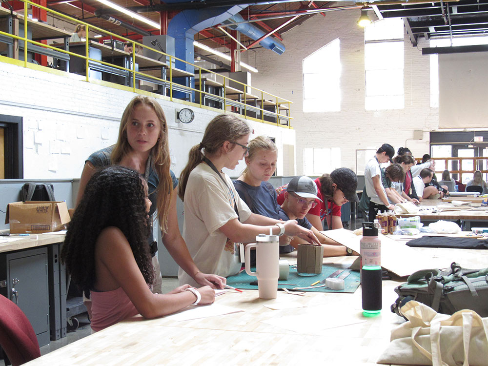 Design Discovery campers working on their projects at a desk in Barn.